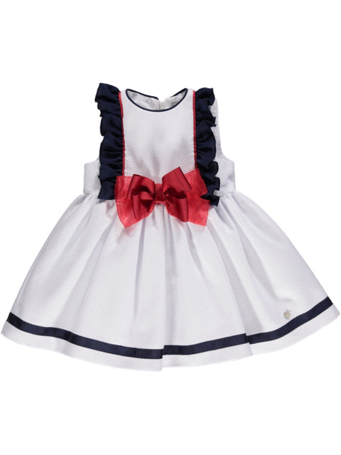 White dress with navy ruffles and red bow